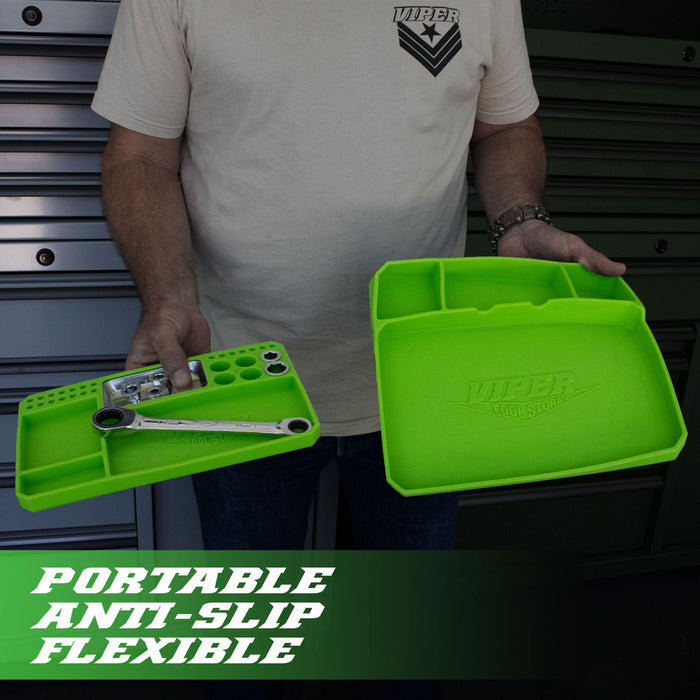 A person holding two lime green silicone tool trays with hand tools in the compartments