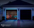 Garage door with a colorful design of a clown and text, illuminated by blue lights at night.