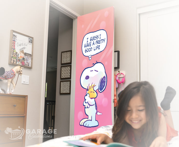 Girl reading a book with a Snoopy-themed door in the background.