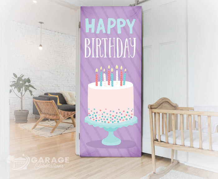 Decorative birthday banner with cake and candles in a room with a crib and plant.