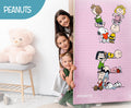 Children peeking from behind a door with Peanuts character illustrations, featuring a teddy bear and 'Peanuts' branding.