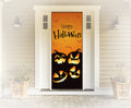 Halloween-themed door cover with pumpkins and 'Happy Halloween' text on a house exterior.