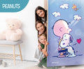 Children peeking from behind a door with a Peanuts-themed poster, featuring Snoopy and Woodstock.